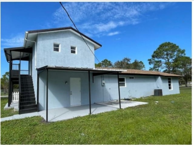 rear view of property with a lawn, a patio area, and central AC