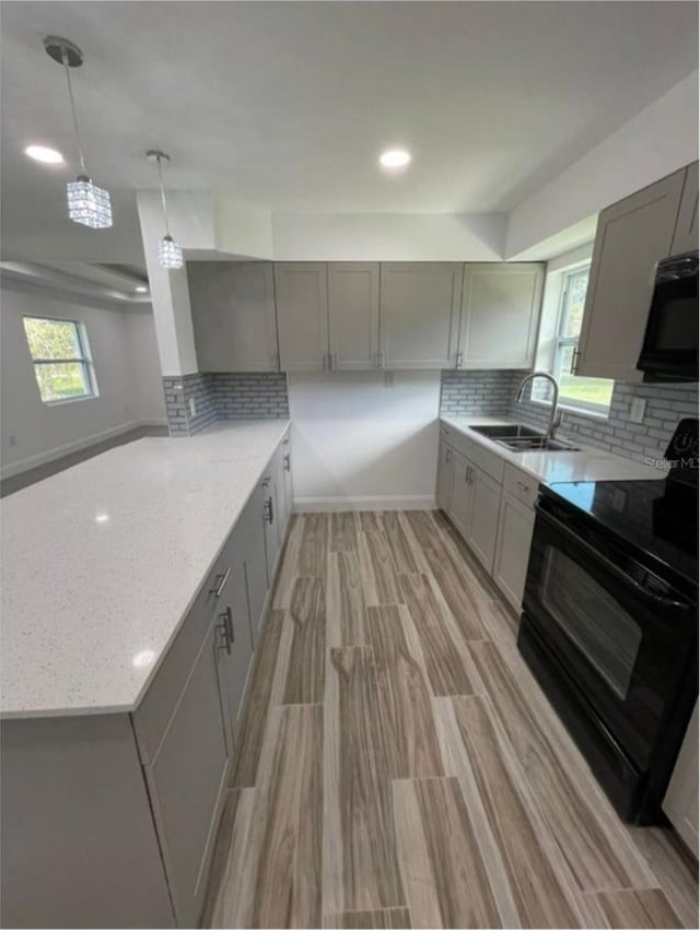 kitchen featuring gray cabinetry, light stone countertops, sink, light hardwood / wood-style floors, and black appliances