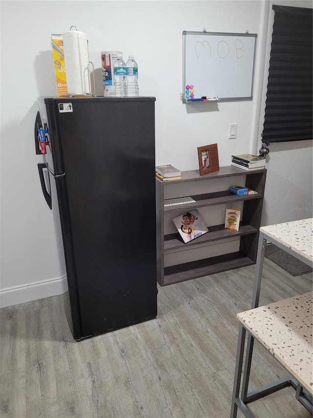 details with black refrigerator and light hardwood / wood-style flooring