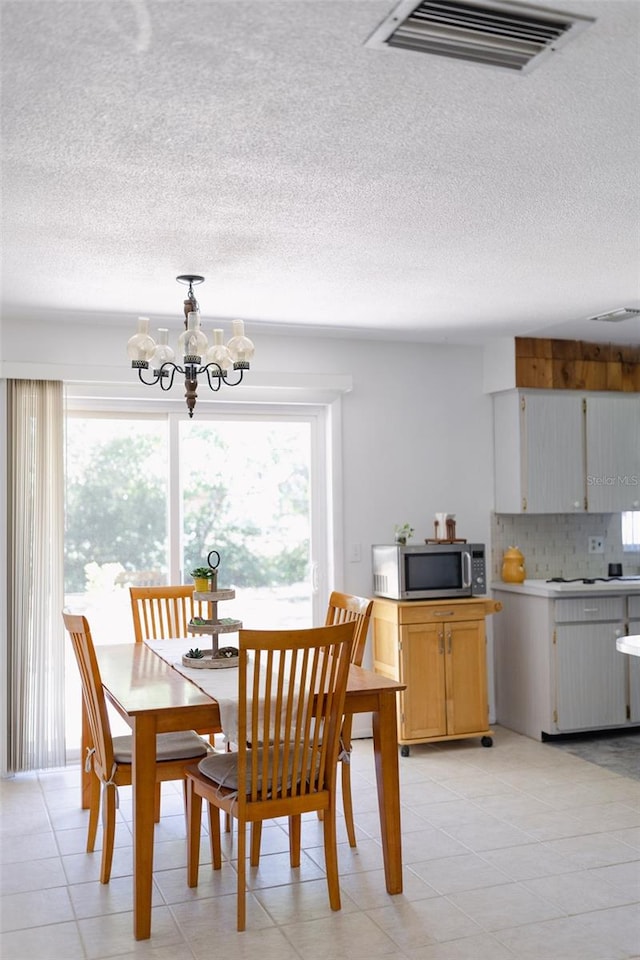 dining space with light tile patterned flooring, a textured ceiling, and an inviting chandelier