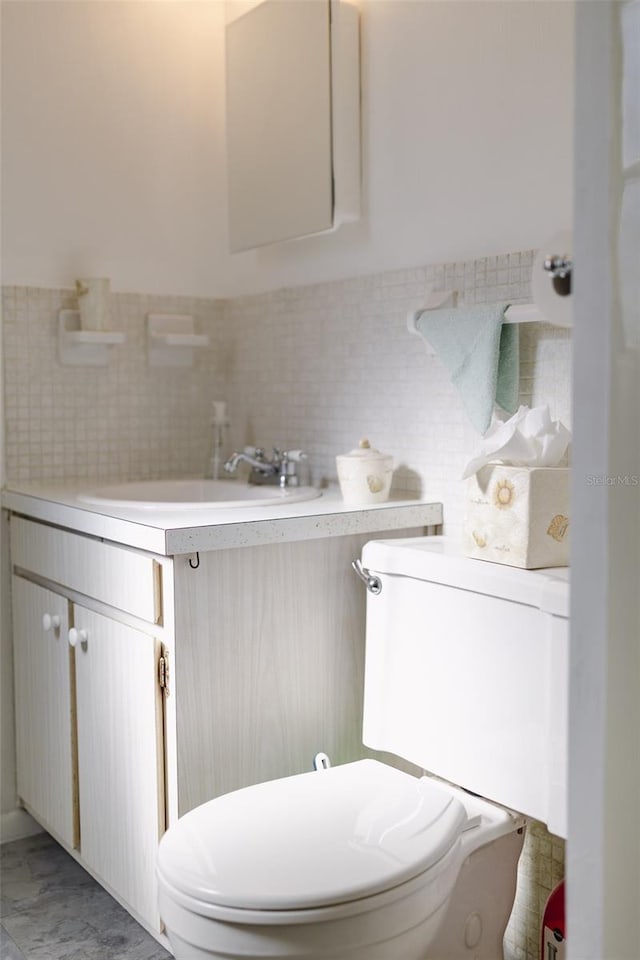 bathroom featuring vanity, toilet, and tile walls