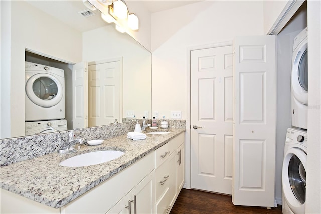 clothes washing area featuring stacked washer / dryer, sink, and dark wood-type flooring