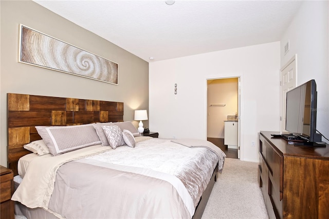 bedroom featuring light carpet and ensuite bath