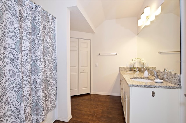 bathroom with vanity, hardwood / wood-style flooring, walk in shower, and lofted ceiling