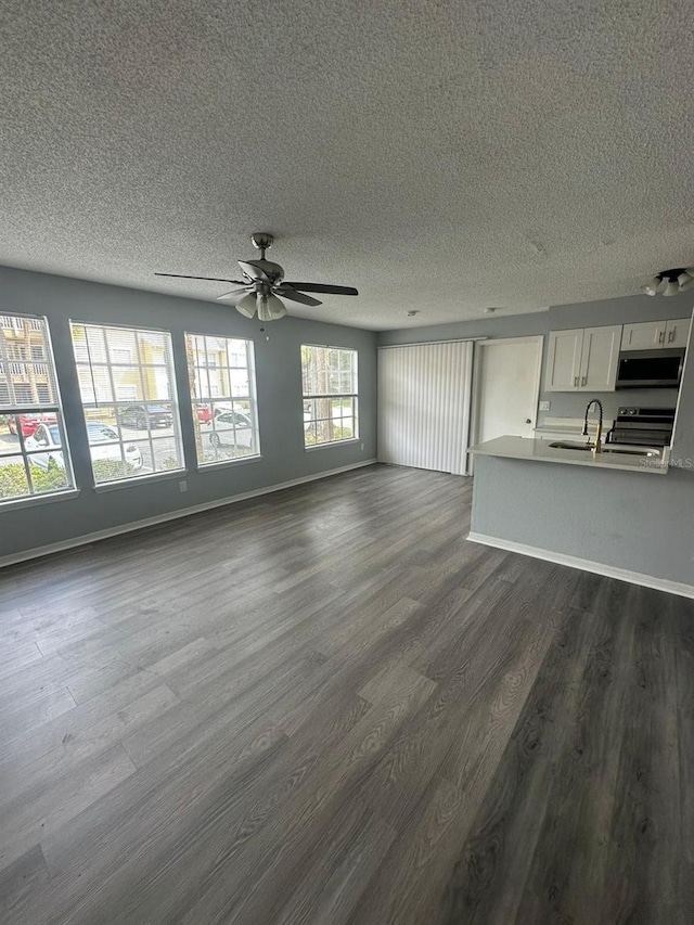 unfurnished living room featuring ceiling fan, dark hardwood / wood-style flooring, a textured ceiling, and sink