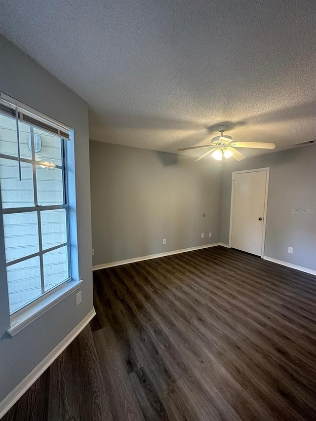 empty room with a textured ceiling, dark hardwood / wood-style floors, and ceiling fan