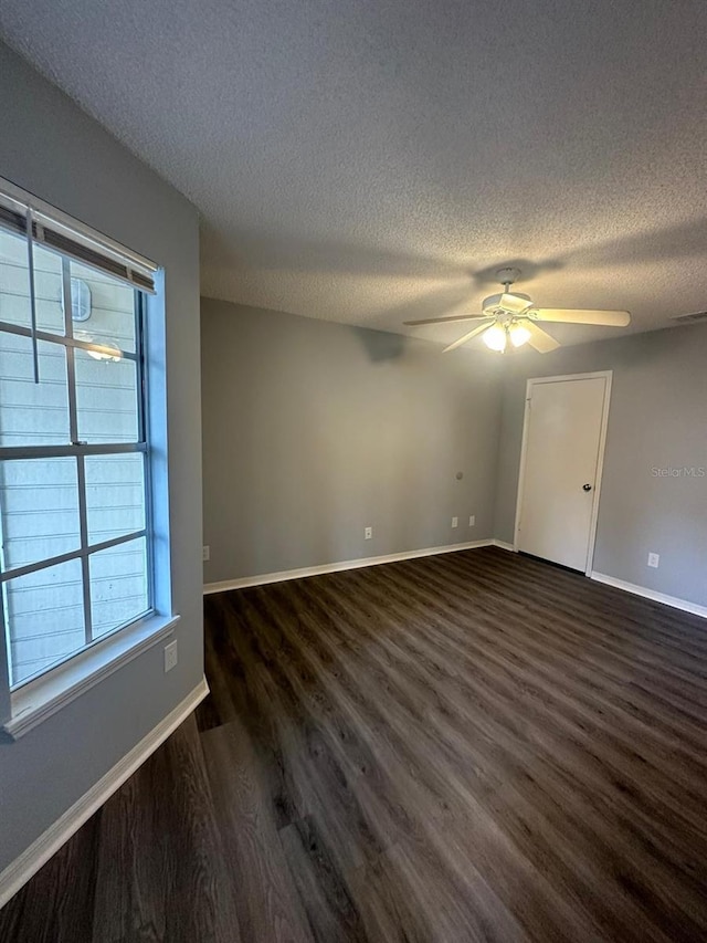 empty room featuring a textured ceiling, dark hardwood / wood-style floors, and ceiling fan