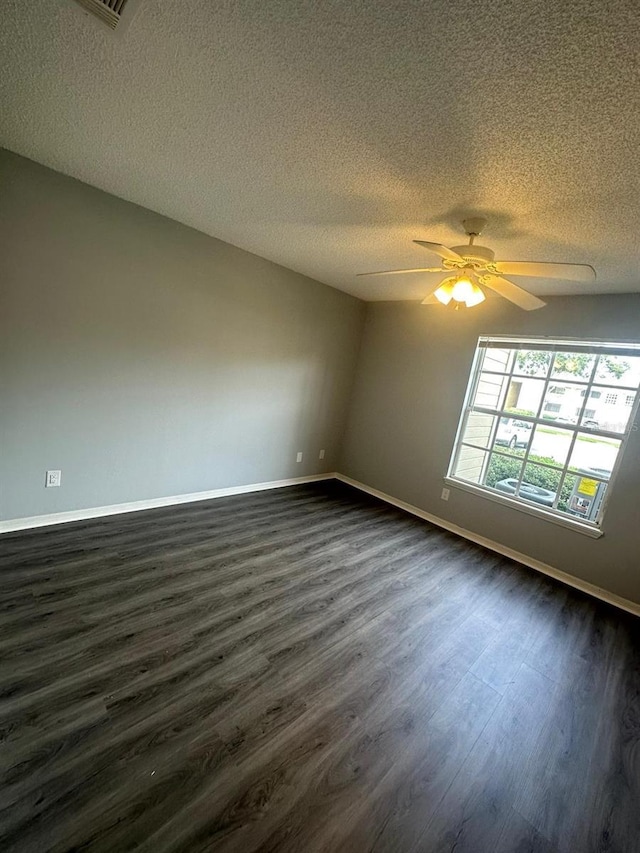 empty room featuring ceiling fan, dark hardwood / wood-style flooring, and a textured ceiling