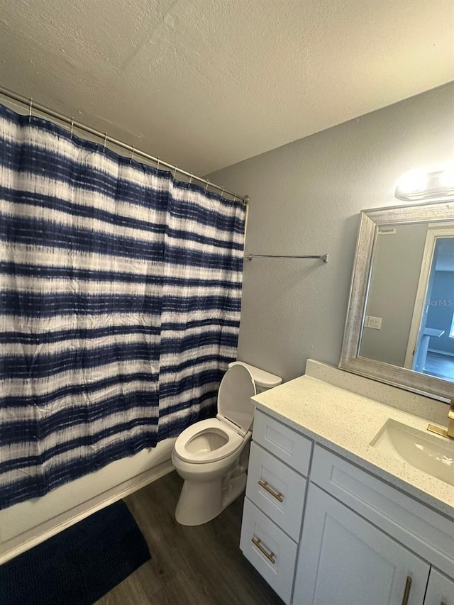 full bathroom featuring wood-type flooring, a textured ceiling, toilet, shower / bath combo with shower curtain, and vanity