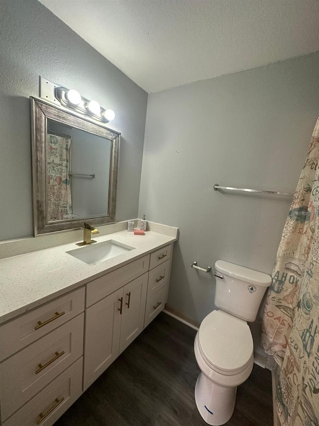 bathroom featuring wood-type flooring, vanity, a textured ceiling, and toilet