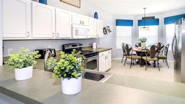 kitchen featuring hanging light fixtures, white cabinets, stainless steel appliances, and light tile patterned floors