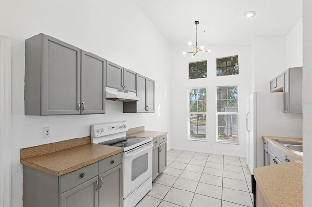 kitchen with white range with electric stovetop, gray cabinetry, light tile patterned flooring, and a notable chandelier