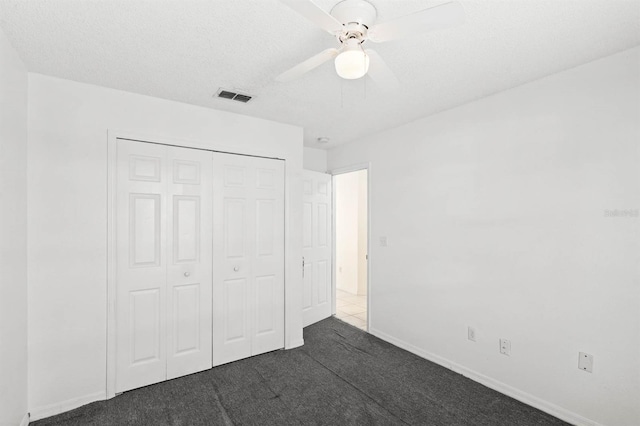 unfurnished bedroom featuring dark colored carpet, ceiling fan, and a closet