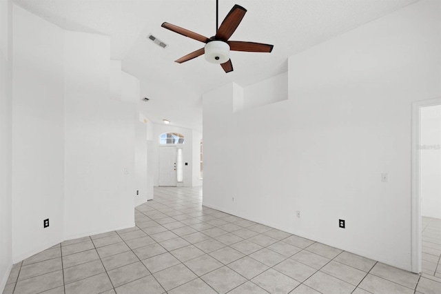 empty room featuring vaulted ceiling, ceiling fan, and light tile patterned flooring