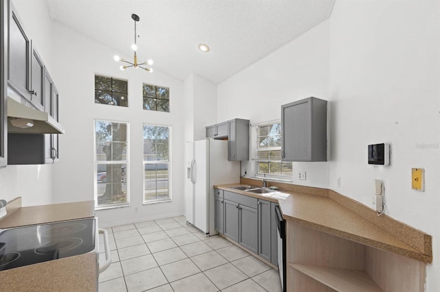 kitchen featuring stove, gray cabinetry, white refrigerator with ice dispenser, an inviting chandelier, and hanging light fixtures