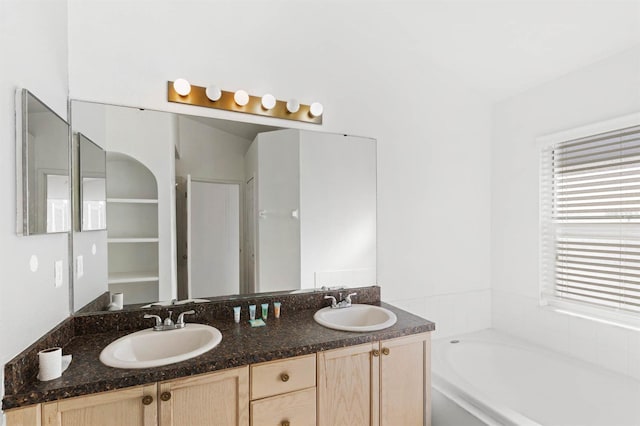 bathroom with a washtub, vanity, and a healthy amount of sunlight