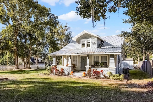 view of front of property featuring covered porch, central air condition unit, and a front yard