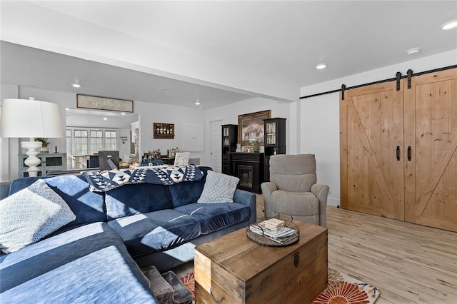 living room with a barn door and light hardwood / wood-style flooring