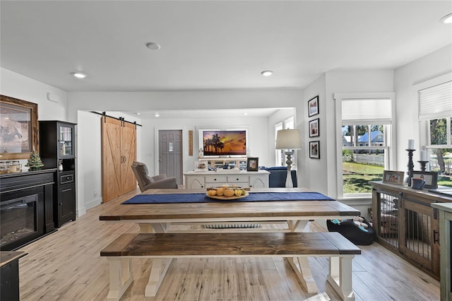 dining area with a barn door and light hardwood / wood-style floors