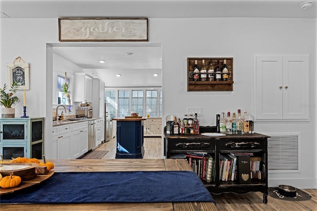 bar featuring sink, white cabinets, and light hardwood / wood-style floors