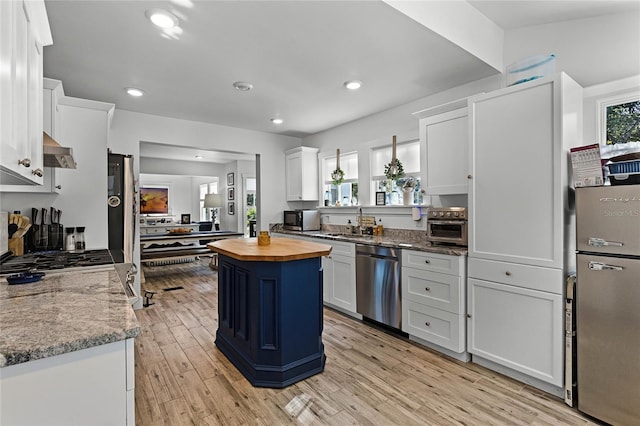 kitchen with wood counters, a center island, stainless steel appliances, and white cabinetry