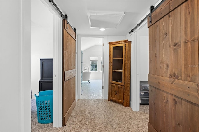 hallway featuring a barn door, light colored carpet, and vaulted ceiling