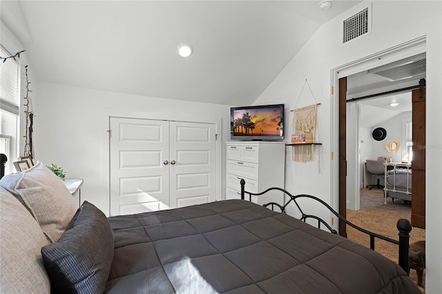 bedroom with carpet flooring, a barn door, vaulted ceiling, and a closet