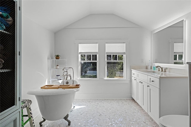 bathroom with a tub to relax in, vanity, and vaulted ceiling