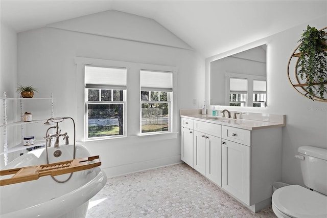 bathroom with vanity, a bathtub, toilet, and vaulted ceiling