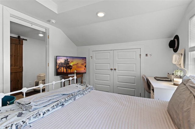 bedroom with a barn door, lofted ceiling, and a closet