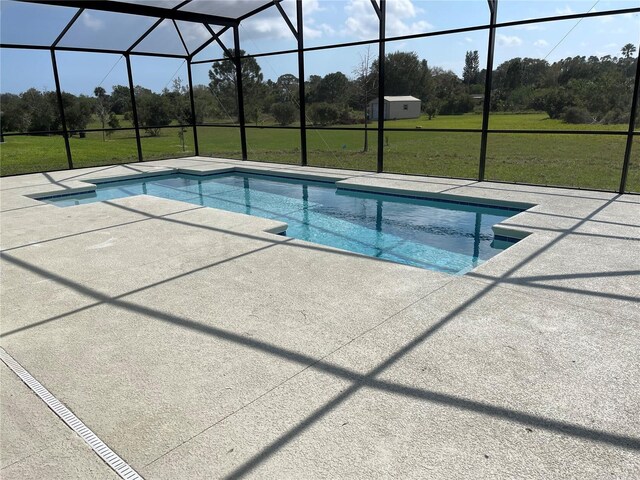 view of swimming pool with a patio area, glass enclosure, and a lawn