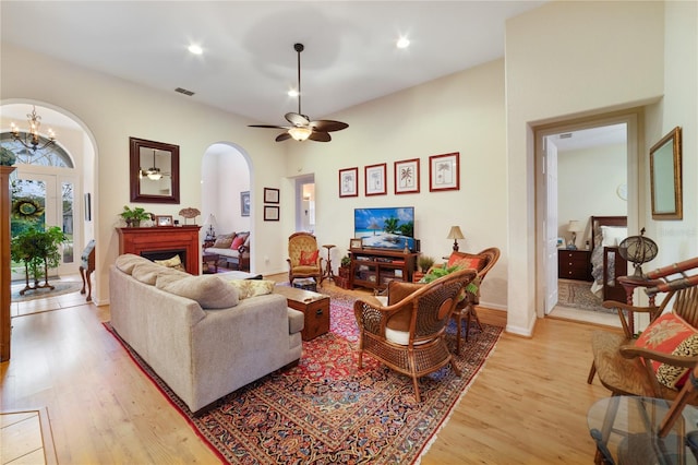 living room with ceiling fan with notable chandelier and light hardwood / wood-style flooring