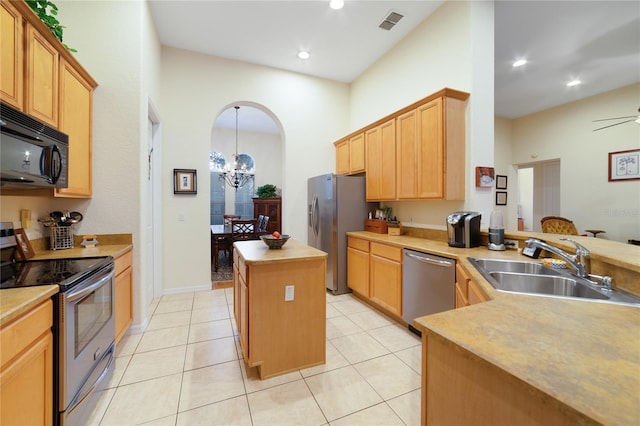 kitchen with sink, a kitchen island, stainless steel appliances, and light tile patterned floors