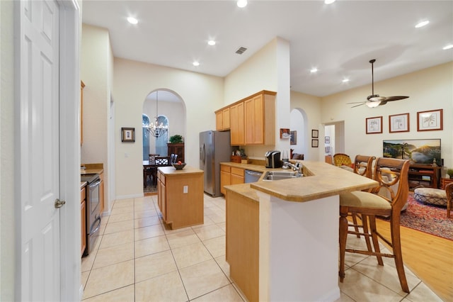 kitchen featuring sink, stainless steel appliances, kitchen peninsula, a breakfast bar, and ceiling fan with notable chandelier