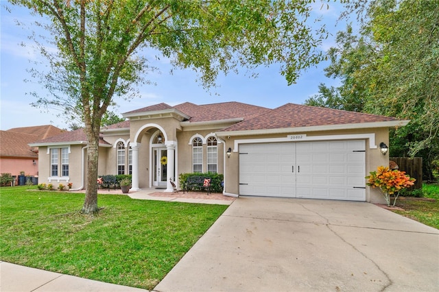 mediterranean / spanish home featuring a garage and a front lawn