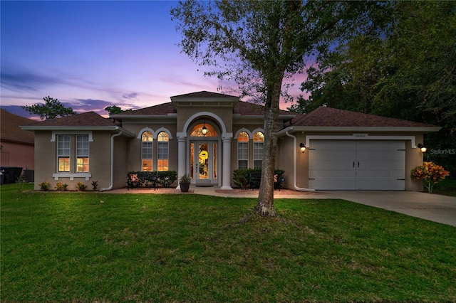 mediterranean / spanish home with a garage and a lawn