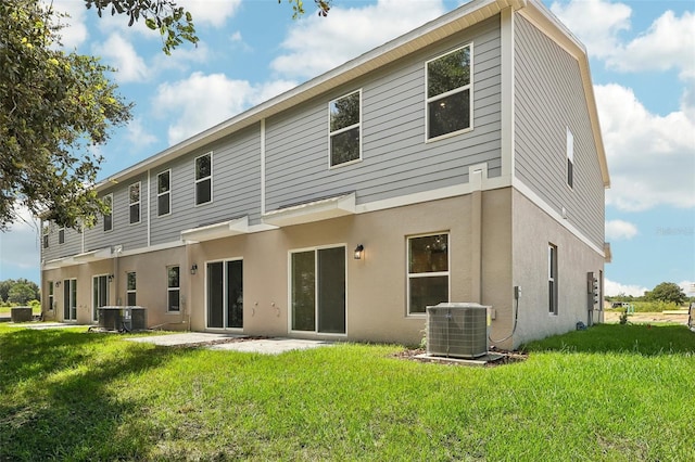 rear view of house featuring cooling unit, a patio area, and a lawn