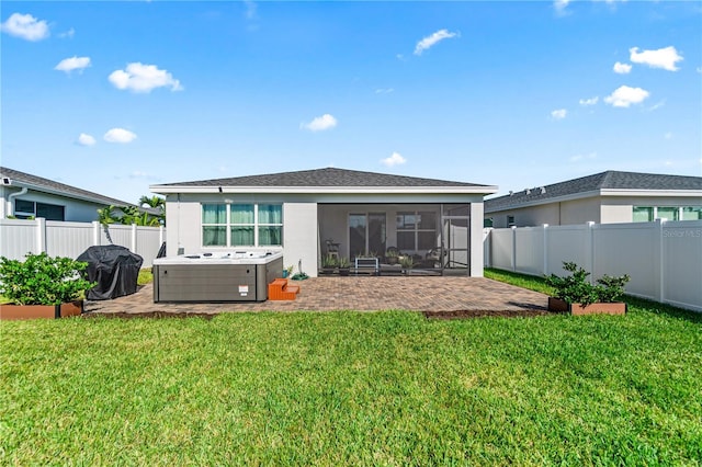 back of house with a hot tub, a lawn, a patio area, and a sunroom