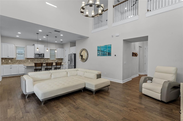 living room with a chandelier, a high ceiling, and dark hardwood / wood-style floors