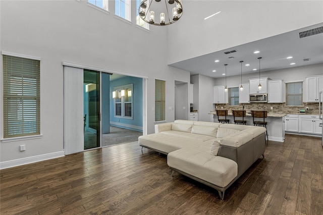 living room featuring dark hardwood / wood-style flooring, a chandelier, and a high ceiling