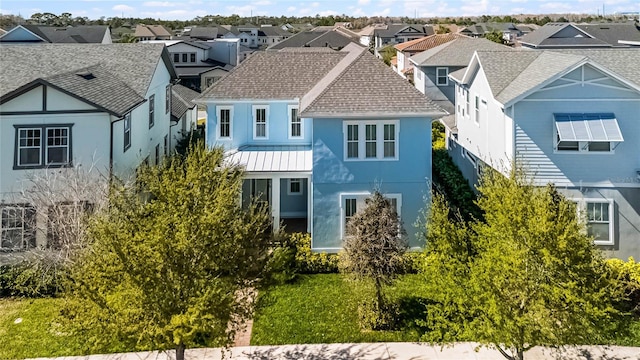 view of front facade featuring roof with shingles, stucco siding, a standing seam roof, metal roof, and a residential view