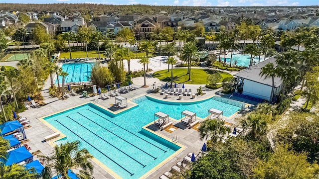 community pool featuring a patio area, fence, and a residential view