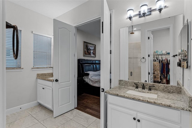 ensuite bathroom featuring a sink, tile patterned flooring, a walk in closet, a shower stall, and two vanities