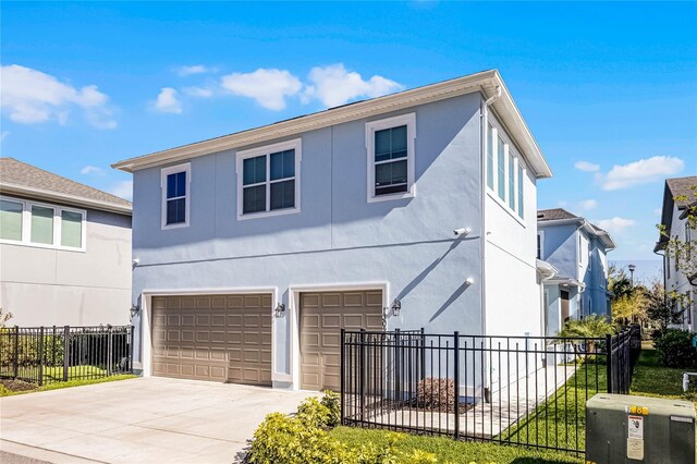 traditional home with a garage, concrete driveway, fence, and stucco siding