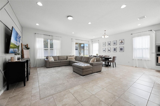 living room with plenty of natural light, light tile patterned floors, a chandelier, and a textured ceiling