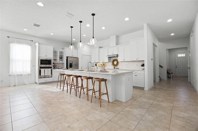 kitchen with white cabinetry, a kitchen island with sink, hanging light fixtures, and stainless steel appliances