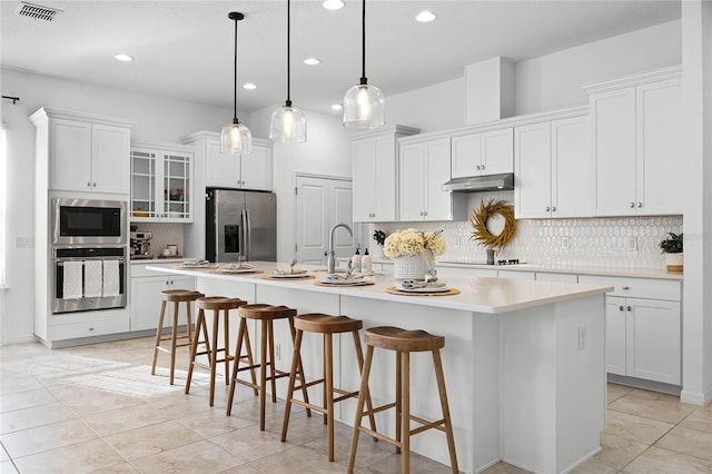 kitchen with white cabinets, stainless steel appliances, and a kitchen island with sink