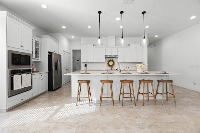 kitchen featuring white cabinets, a kitchen breakfast bar, hanging light fixtures, a large island, and stainless steel appliances