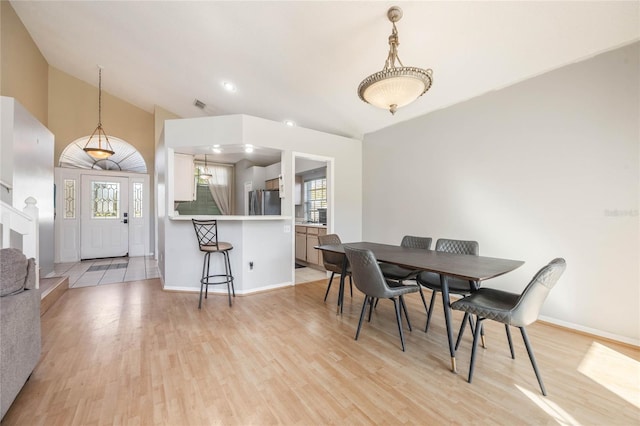 dining room with lofted ceiling and light wood-type flooring