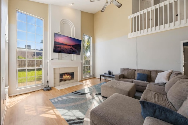 living room with a fireplace, plenty of natural light, wood-type flooring, and a high ceiling